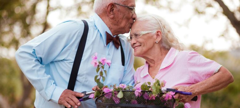 Ein alter Mann küsst eine alte Frau liebevoll auf den Kopf